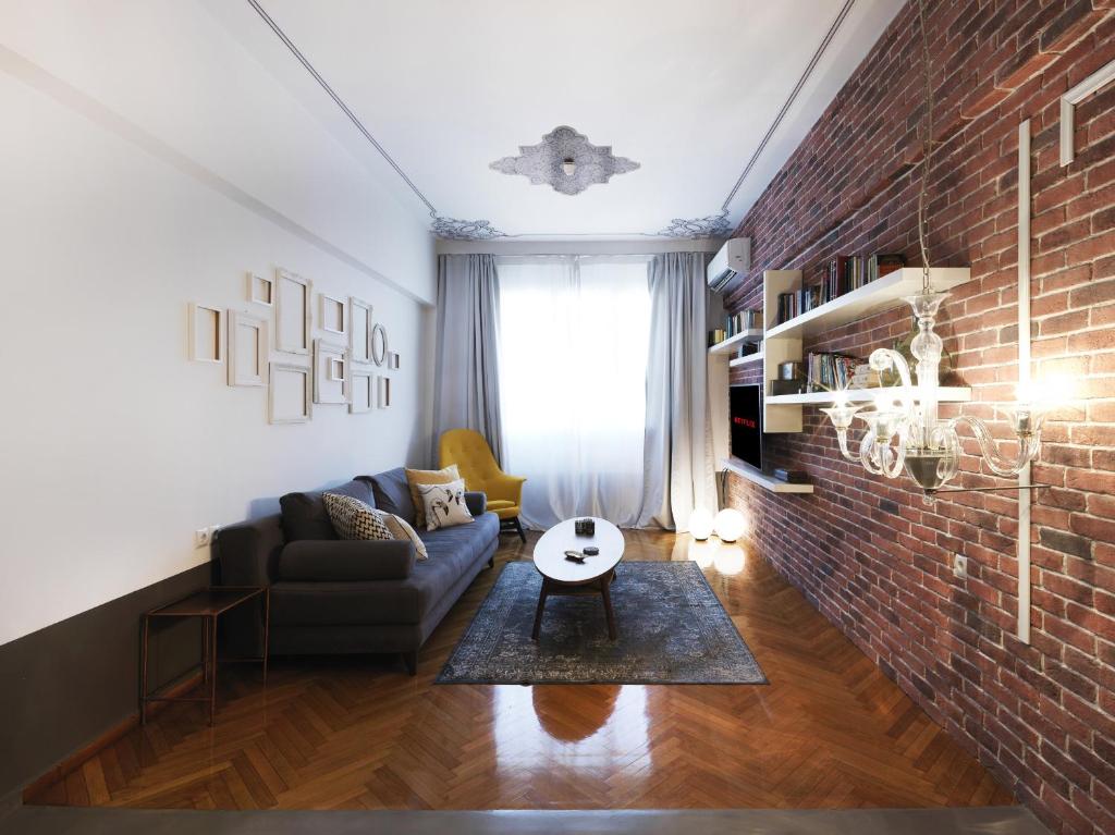 salon z kanapą i ceglaną ścianą w obiekcie Athenian Apartment in the center with Jacuzzi w Atenach