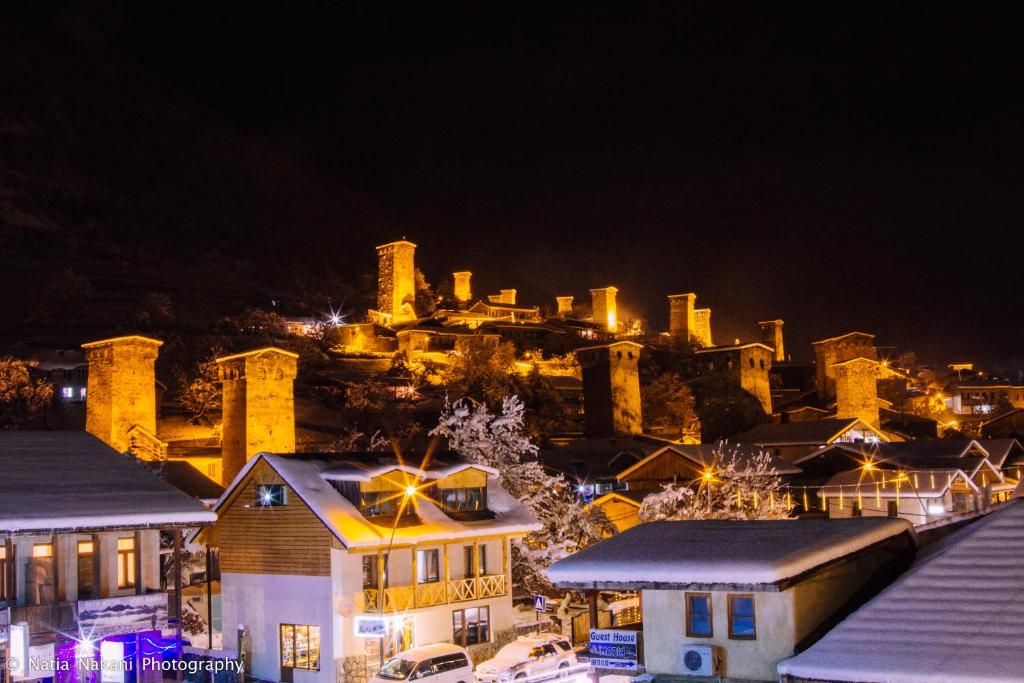 uma cidade iluminada à noite com uma cidade em Hotel Svaneti em Mestia
