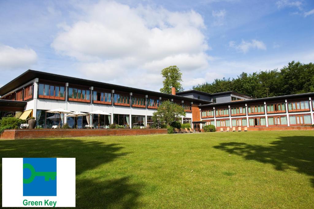 un grand bâtiment avec une pelouse devant lui dans l'établissement Hotel Hesselet, à Nyborg