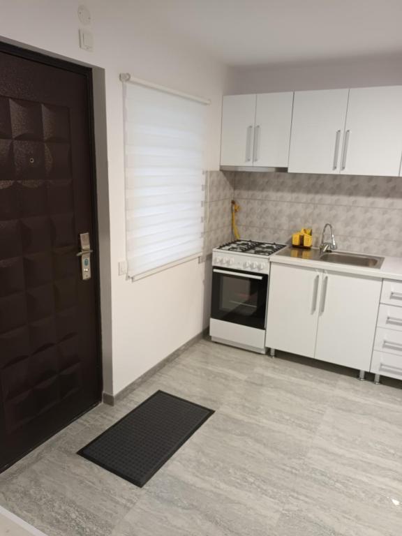 uma cozinha com armários brancos e uma porta preta em apartament de lux em Lupeni
