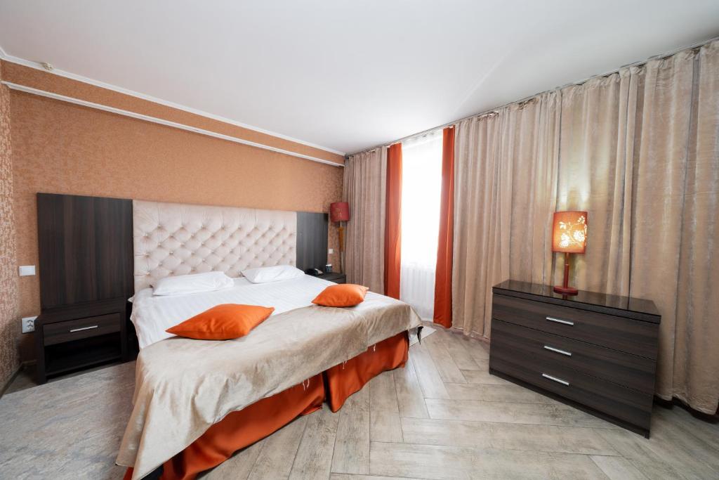 een slaapkamer met een groot bed met oranje kussens bij Ostrov Hotel in Qostanaj