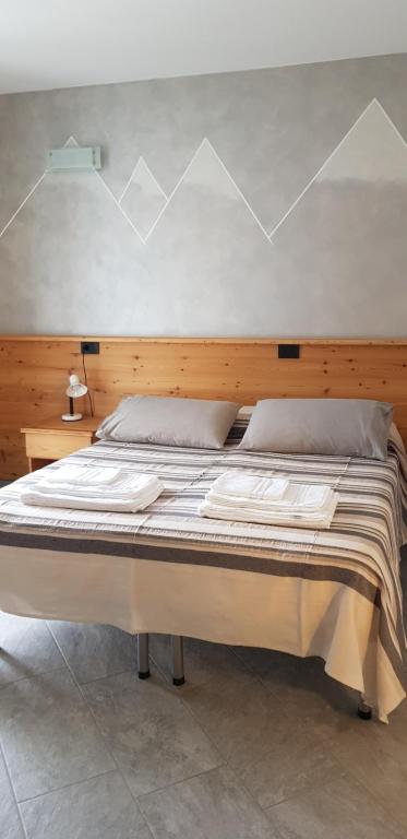 a bedroom with a large bed with a wooden headboard at Il Mulinel agriturismo in Teglio