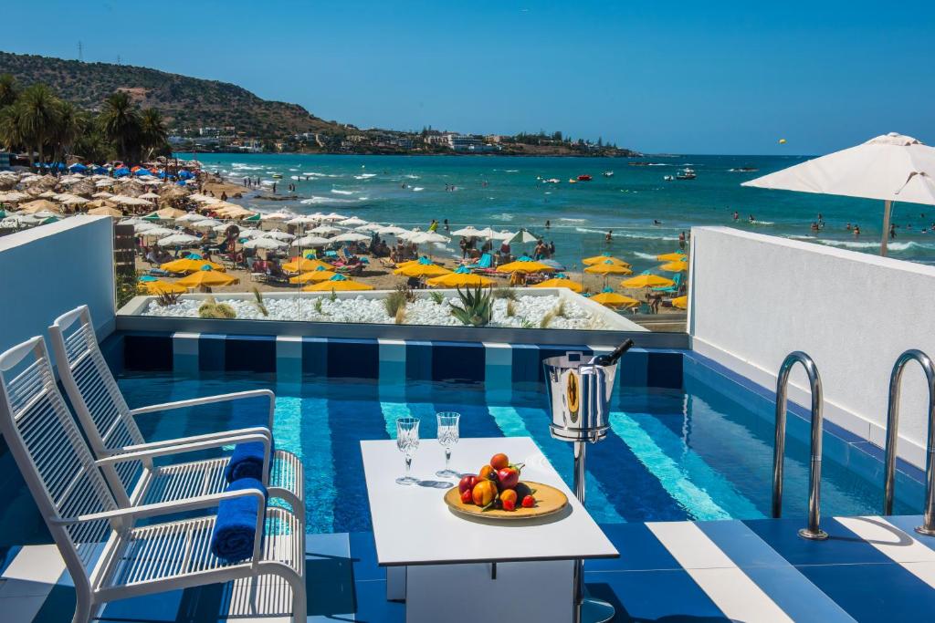einen Tisch mit einer Schale Obst auf einem Balkon mit Strand in der Unterkunft I Resort Beach Hotel & Spa in Stalida