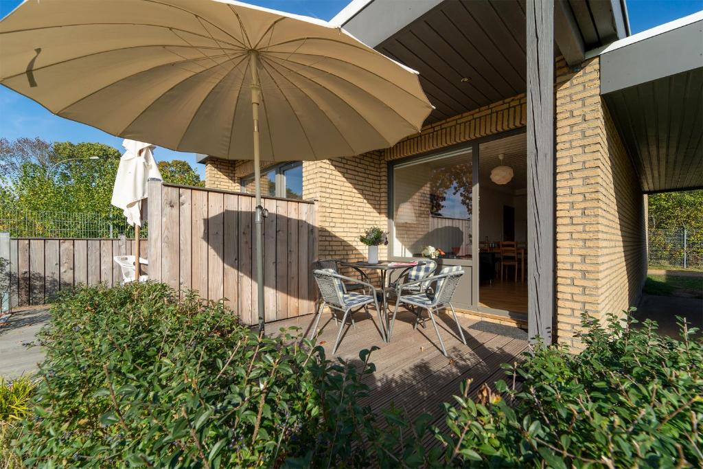 eine Terrasse mit einem Tisch und einem Sonnenschirm in der Unterkunft Blankwasserweg 131 Lensterstrand Oase Bungalow 2 in Lenste