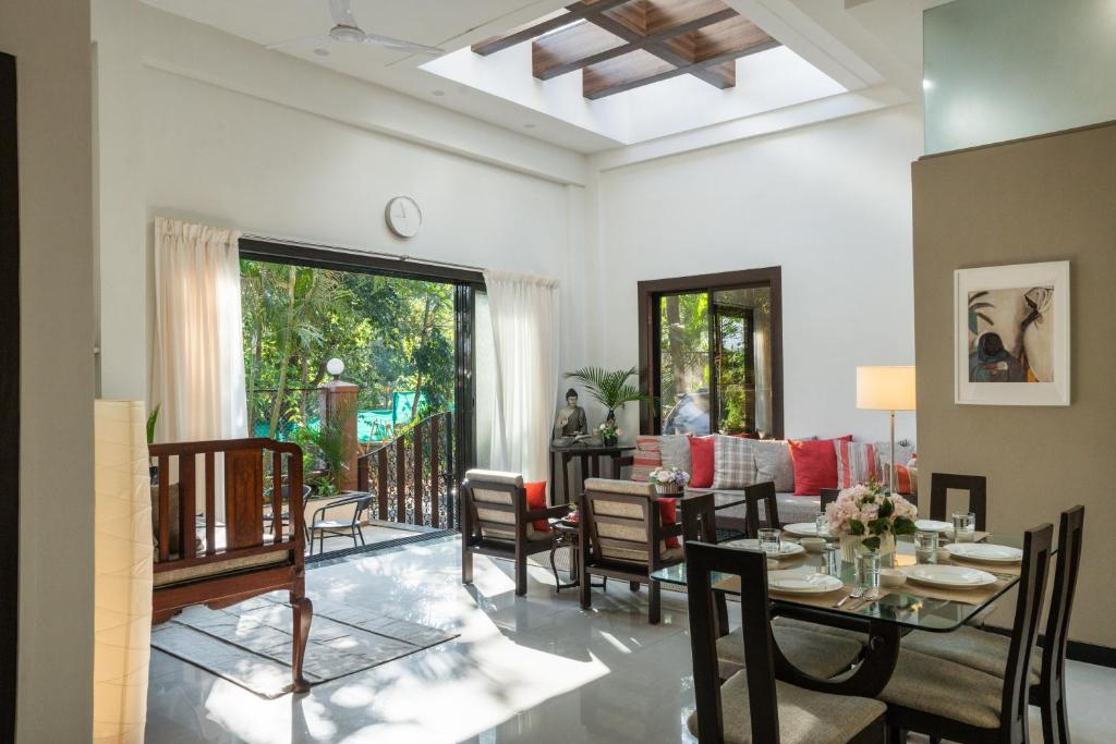 罗纳瓦拉SaffronStays Uno Crest, Lonavala - 4 BDR Artistically Decorated Villa Near Bhushi Dam的带桌椅的客厅