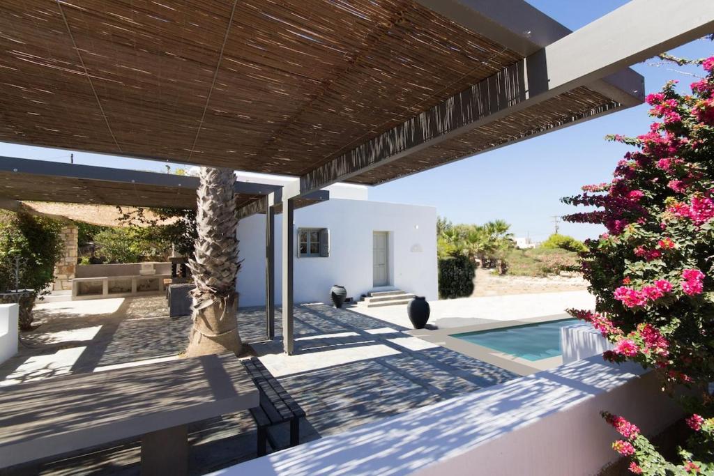a patio with a palm tree and a swimming pool at Villa Aphrodite · Elegant villa, sea views, designer renovation in Ambelas