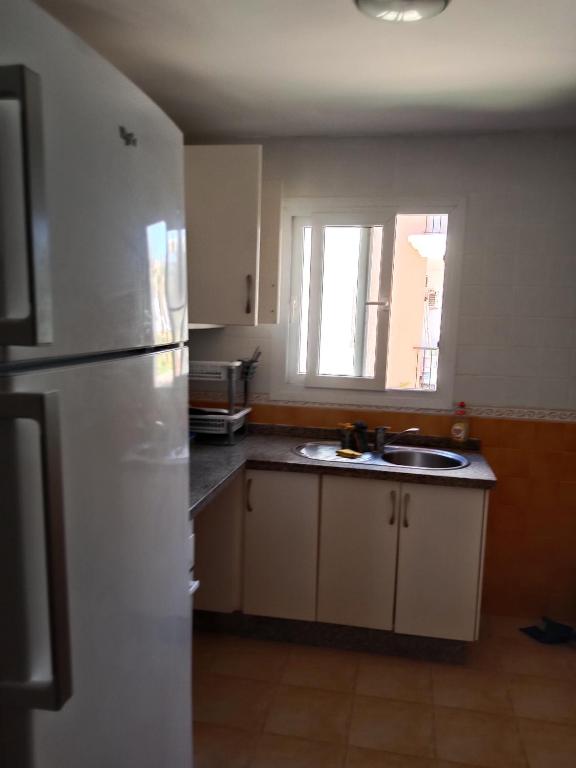a kitchen with a white refrigerator and a sink at Marina Bahia in Saïdia
