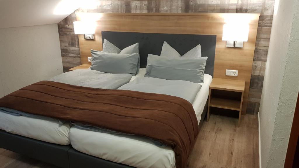 1 dormitorio con 1 cama grande con sábanas y almohadas blancas en Landgasthof Hotel Hirsch en Marktlustenau