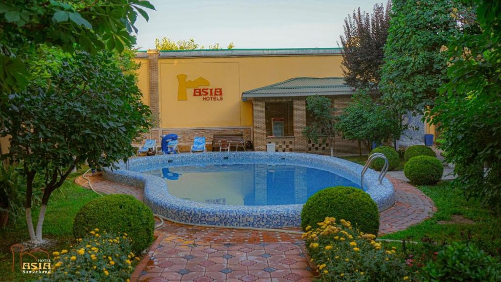 a swimming pool in a yard with a building at Hotel Asia Samarkand in Khodzha-Akhrar