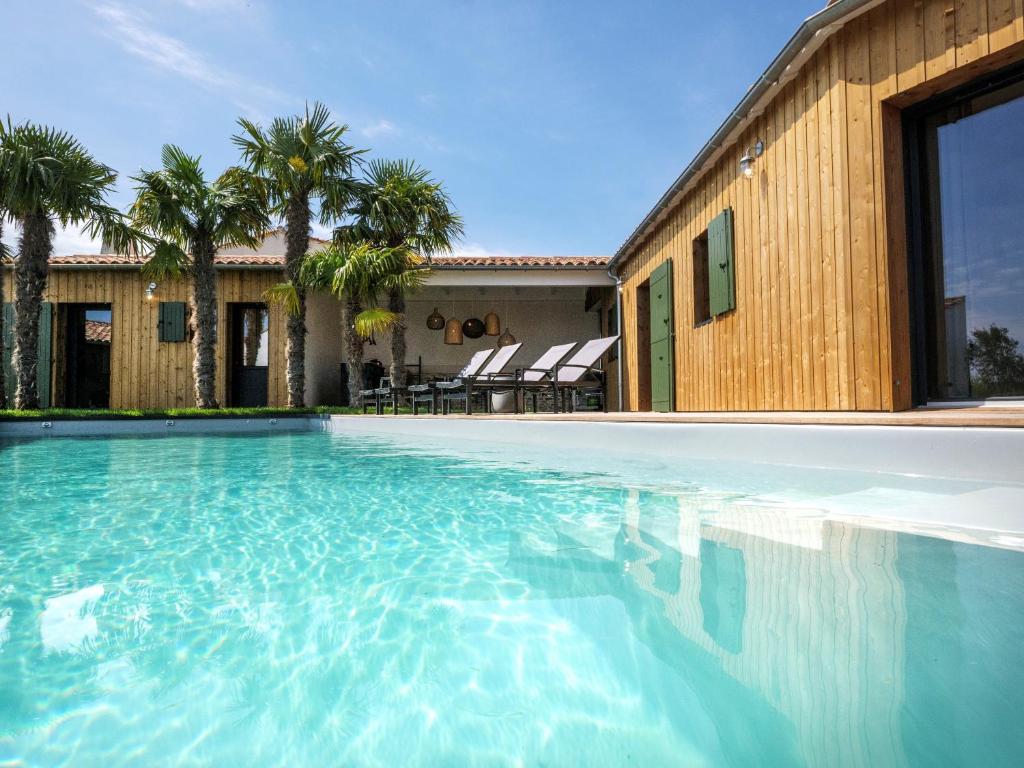 une piscine devant une maison avec des palmiers dans l'établissement La villa Terracotta - Villa de rêve au calme à 900 m de l'océan avec piscine chauffée, à Sainte-Marie de Ré