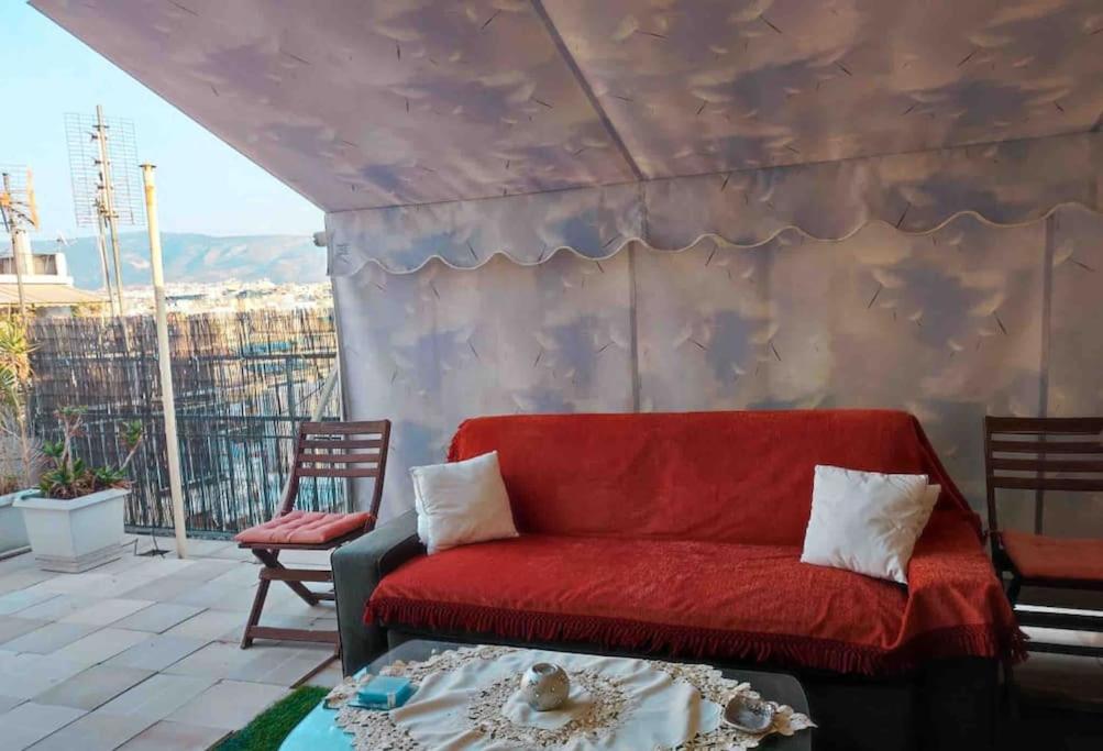 czerwona kanapa siedząca na balkonie w obiekcie Spacious private rooftop studio, mountain and sea view w Atenach