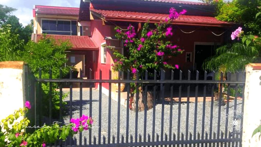 einen Zaun vor einem Haus mit rosa Blumen in der Unterkunft Pousada Tem não tem, Parque Beto Carrero, Penha, SC in Penha