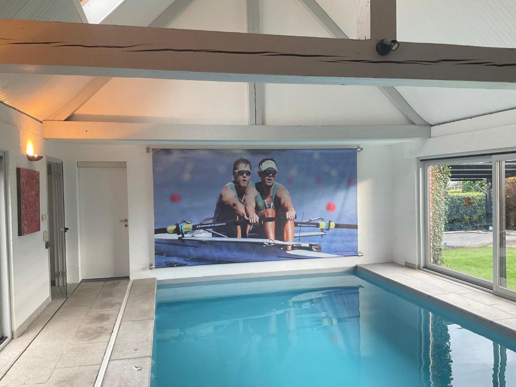 a swimming pool with a picture of two men on the wall at Lovely 1-bedroom appartement Le Joyau with indoor pool and sauna in Lasne