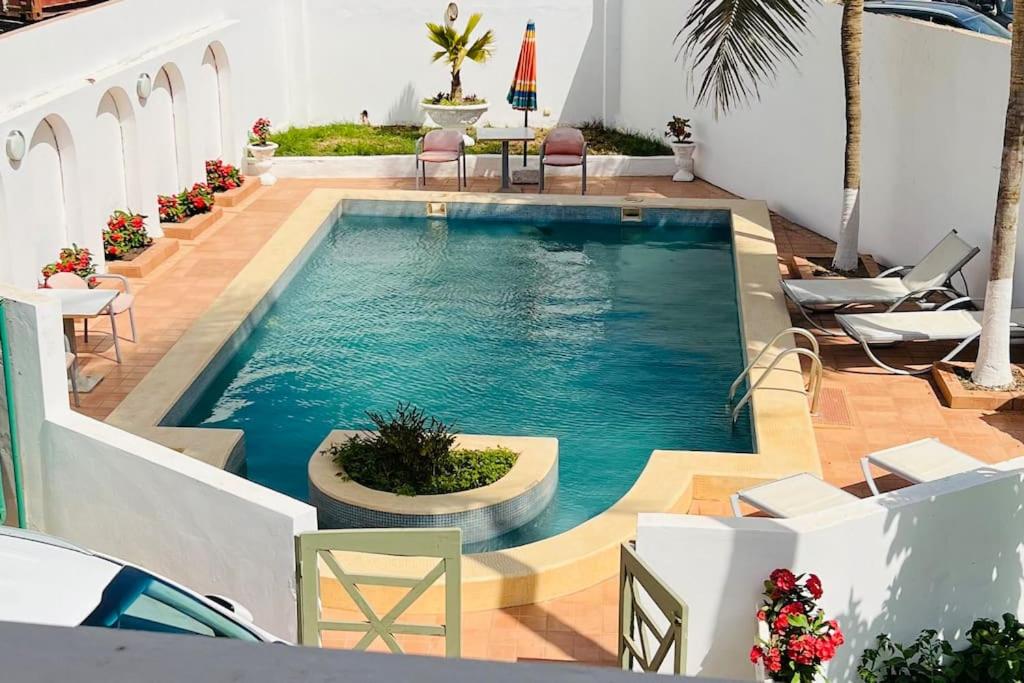 a swimming pool in a house with chairs and a table at TérangaLux Collection Villa Green House Mamelles in Dakar