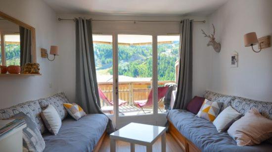 Una sala de estar con un sofá azul y un balcón. en 2 pièces avec terrasse et vue sur les pistes, en Isola 2000