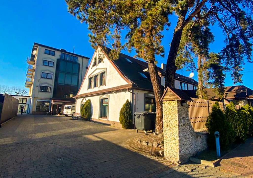 een wit huis met een boom en een gebouw bij Noclegi Prestige in Siewierz