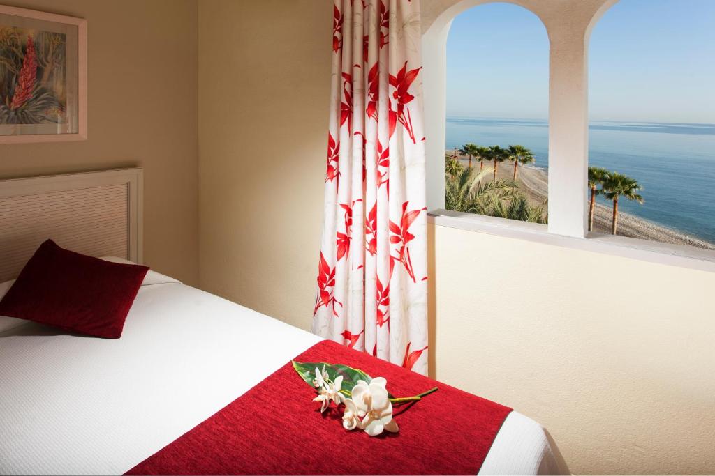 a bedroom with a bed with a red blanket and a window at Ona Marinas de Nerja Spa Resort in Nerja