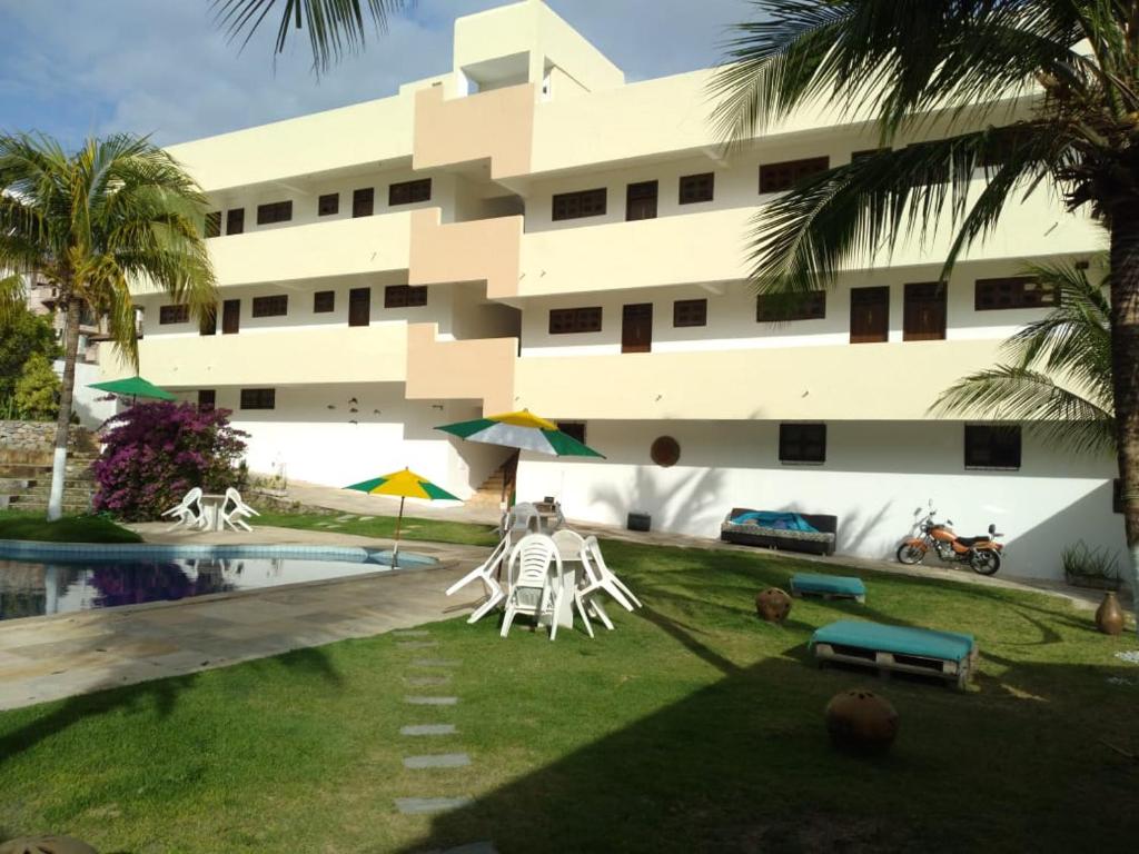 un edificio con piscina, sillas y un edificio en Hotel Pousada Summer Way, en Aquiraz