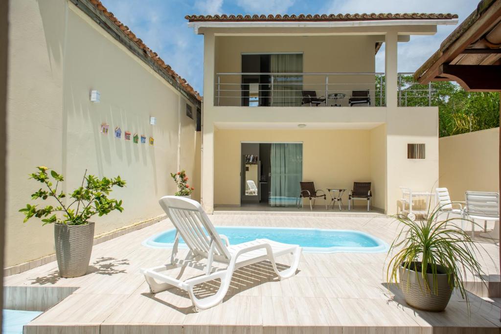 a villa with a swimming pool and two lawn chairs at Quintal da Arte Suites in Arraial d'Ajuda