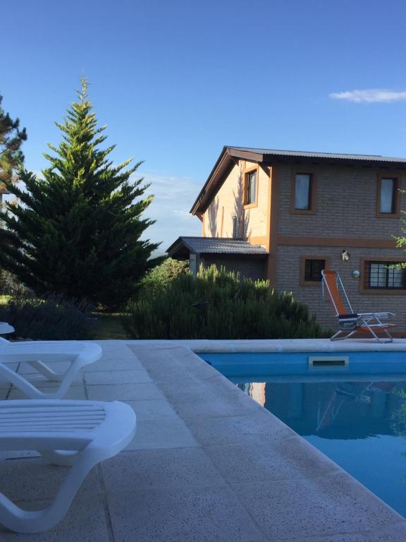 una piscina con 2 sillas y una casa en MiraSierras -casas vacacionales- en Villa General Belgrano