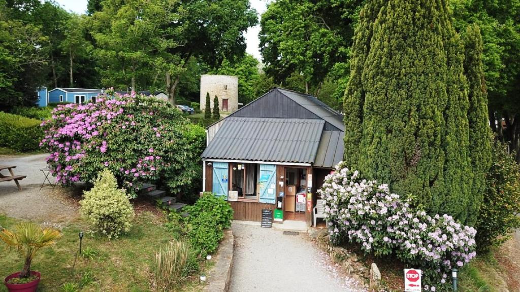 une petite maison dans un jardin fleuri dans l&#39;établissement Camping le Balcon de la Baie, à Saint-Marcan