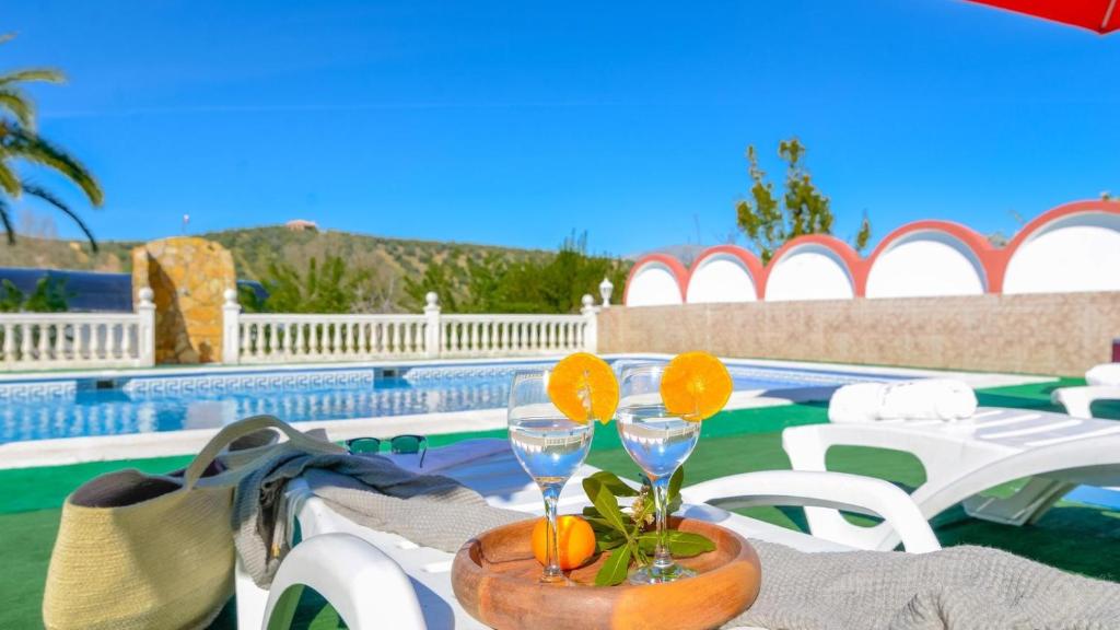 a table with two wine glasses on it next to a pool at Hacienda la Toscana Priego de Córdoba by Ruralidays in Priego de Córdoba