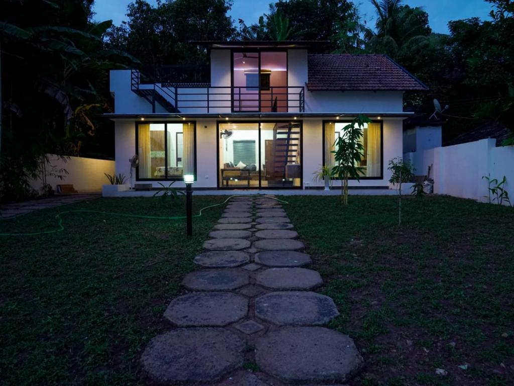 a house with a pathway in front of it at night at Eva Meadows in Kollam