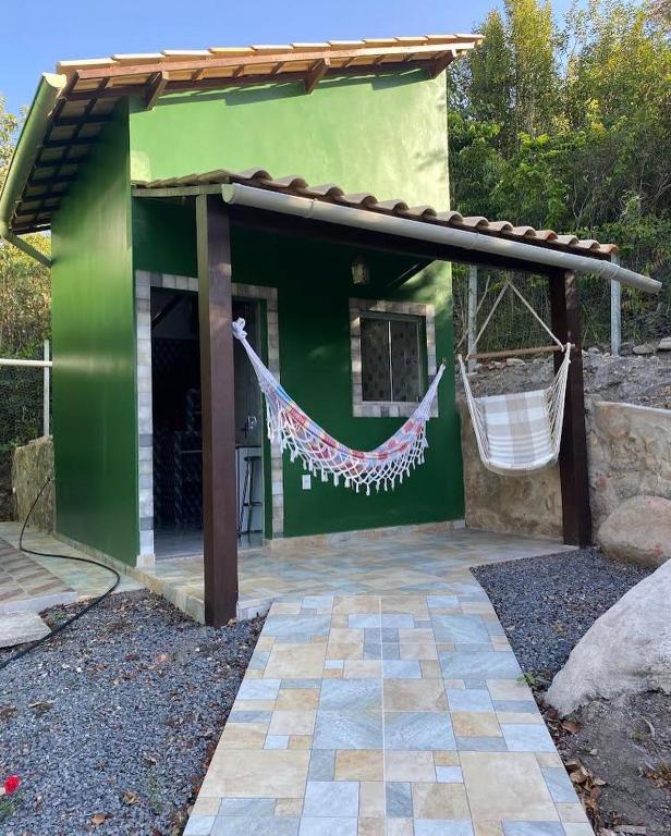 a green building with a hammock in front of it at Micro casa com vista para o Morrão - Vale do Capão in Vale do Capao