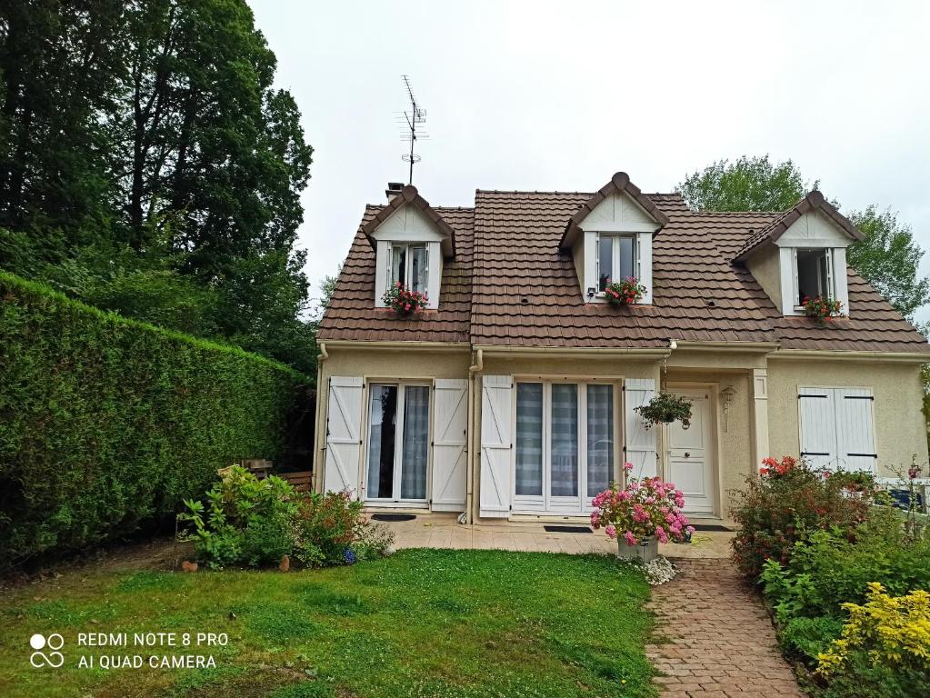 una casa con dos ventanas y flores en el patio en Chambre d hôte à 20 min de VERSAILLES, en Le Mesnil-Saint-Denis