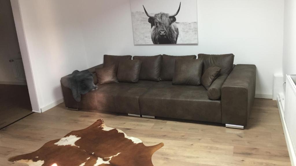un sofá marrón en una sala de estar con un toro en la pared en Bauernhaus zwischen Rheingau und dem Taunus, en Schlangenbad
