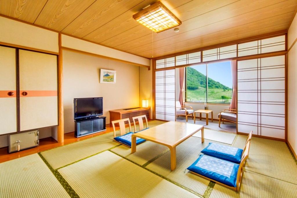 a living room with a table and a tv at Kyukamura Oku-Daisen in Daisen