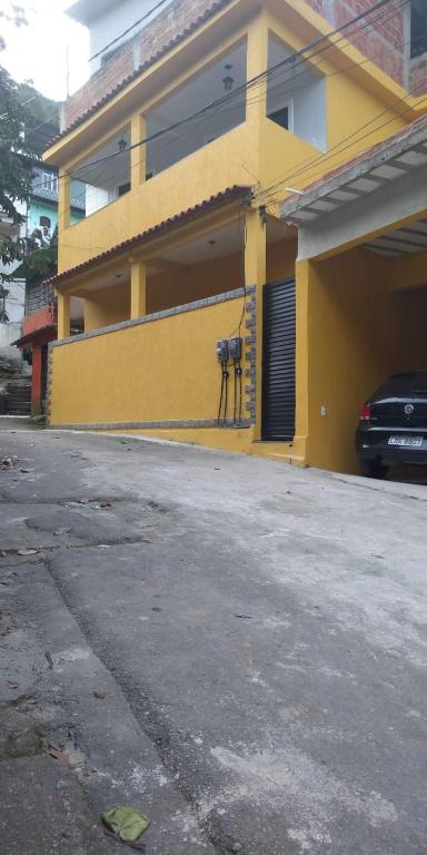 un edificio amarillo con un coche aparcado delante de él en Casa familiar en Angra dos Reis