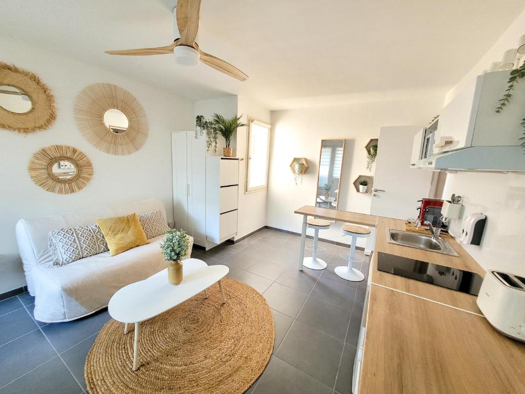 ein Wohnzimmer mit einem weißen Sofa und einer Küche in der Unterkunft Studio 24m² Montpellier - Hôpitaux facultés Centre in Montpellier