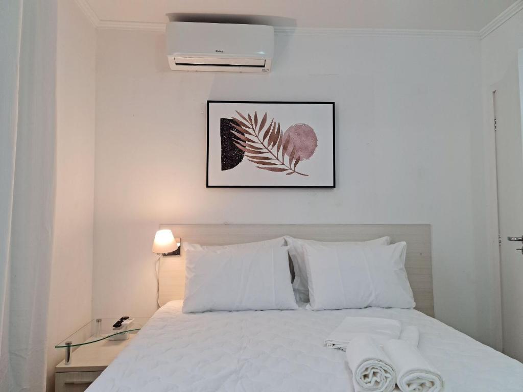 Un dormitorio con una cama blanca y una foto en la pared en Apartamento 604 - Centro BC - Vista Mar, en Balneário Camboriú
