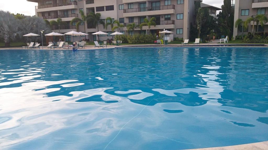 a large pool of blue water in front of a building at Beach Class Eco Life in Porto De Galinhas