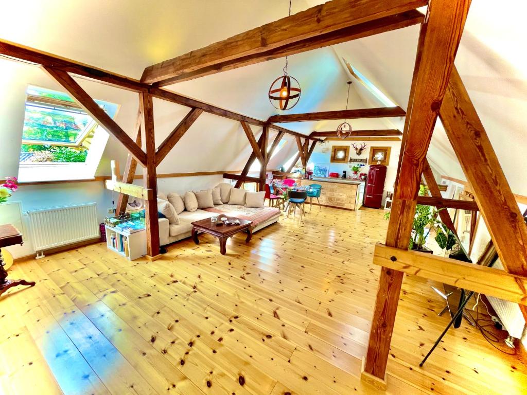 una sala de estar con suelo de madera y una habitación grande con vigas de madera. en Historisches Retro Loft 120m2 + Garten & Seenähe, en Schwielowsee