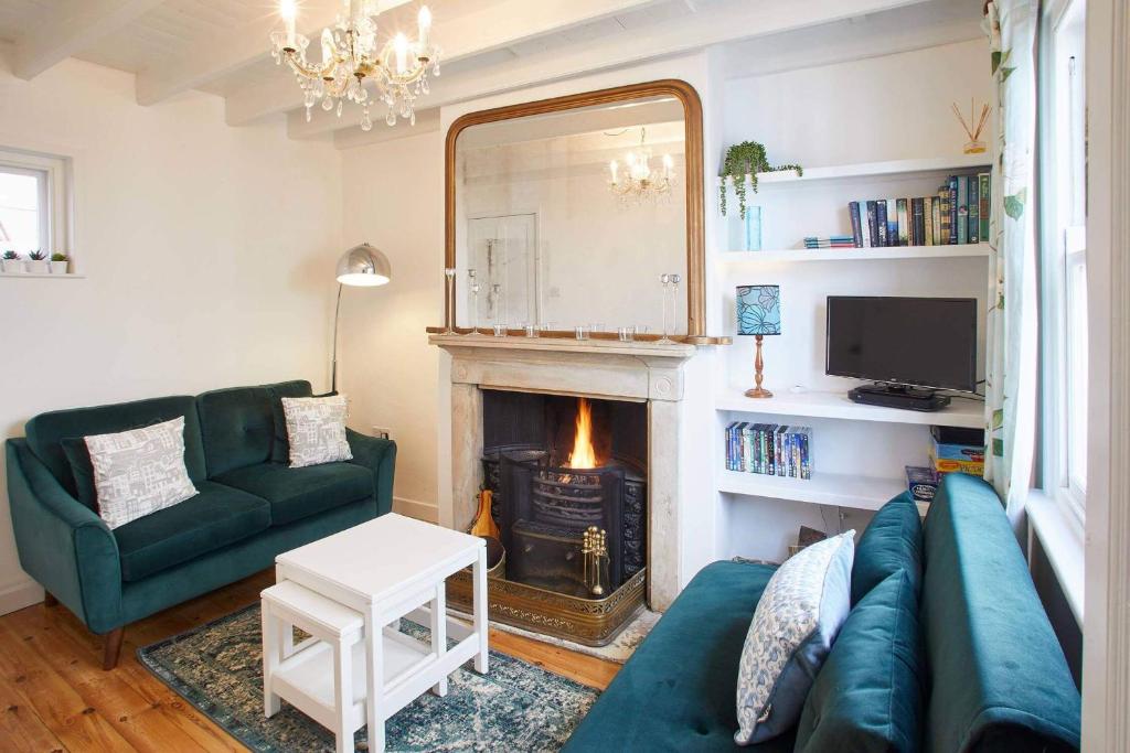 a living room with a green couch and a fireplace at Host & Stay - Gun Gutter House in Staithes