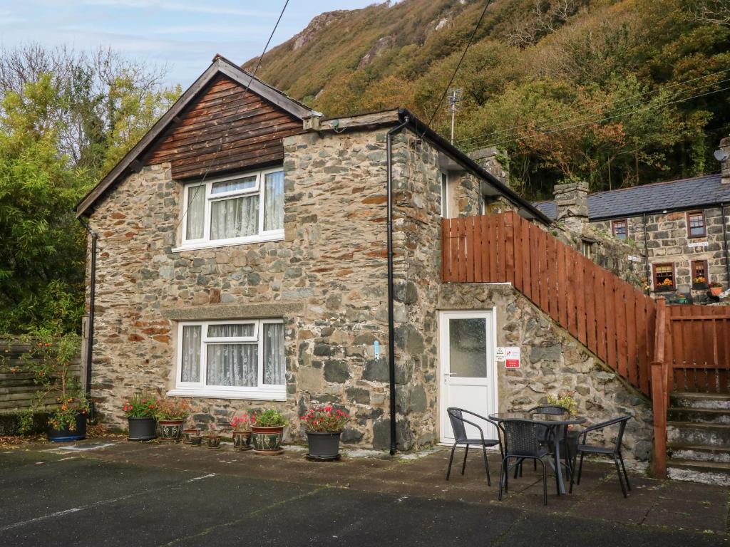 a stone house with a table and chairs in front of it at Ground Floor Apartment in Porthmadog