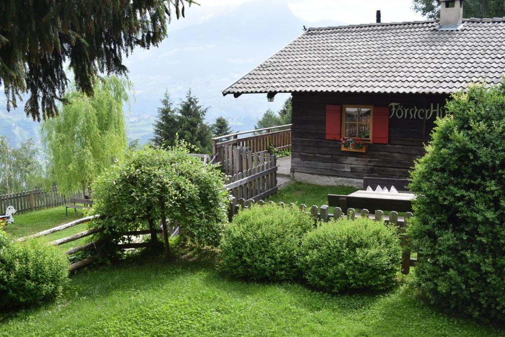 una baita di tronchi con una porta rossa in un cortile di Brünnl's Försterhütte a Parcines