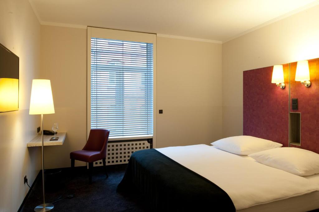 a hotel room with a bed and a desk and a window at Hotel Topas Frankfurt City in Frankfurt/Main