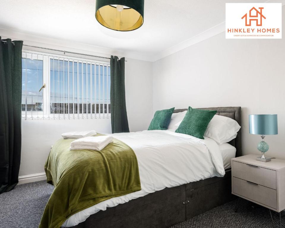 a bedroom with a bed with green pillows and a window at Spacious 3 bedroom house with wifi and car parking By Hinkley Homes Short Lets & Serviced Accommodation in Waterloo