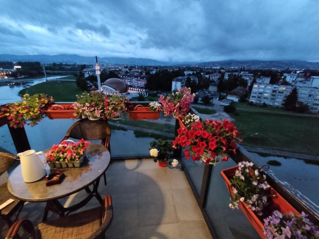 einen Balkon mit einem Tisch und Blumen darauf in der Unterkunft شقة نهر اليجا in Sarajevo