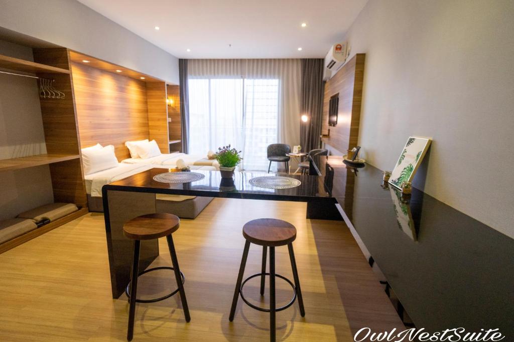 uma sala de estar com uma cozinha com um balcão e bancos em Owl Nest Suite' at aeropod sovo em Kota Kinabalu
