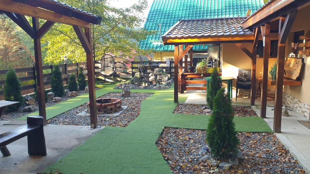 einen Garten mit grünem Gras und einem Holzpavillon in der Unterkunft Cabana Moroșanca-Peștiș in Peştiş