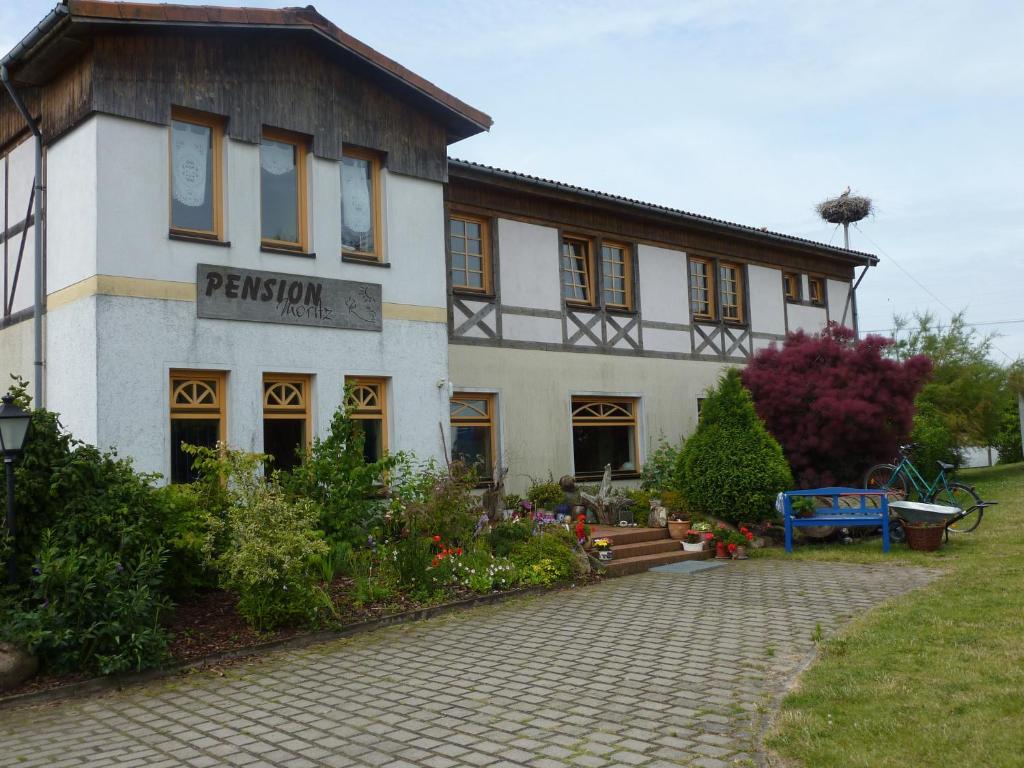 ein weißes Gebäude mit einem Schild auf der Vorderseite in der Unterkunft Pension Moritz und Hofladen unterm Storchennest -16303 Schwedt,Schwedter Allee1 in Schwedt