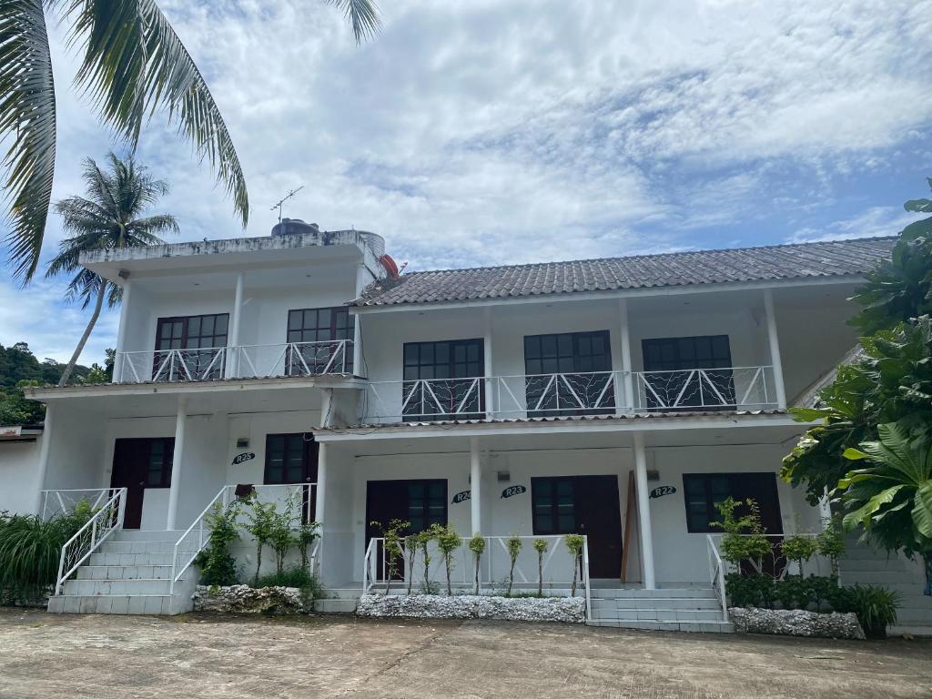 a white building with a balcony and palm trees at White house bailan resort in Ko Chang