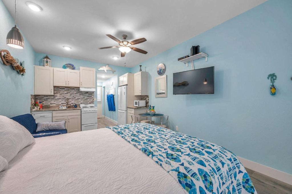 Picturesque Waterfront Studio في كليرووتر بيتش: غرفة نوم زرقاء مع سرير ومطبخ