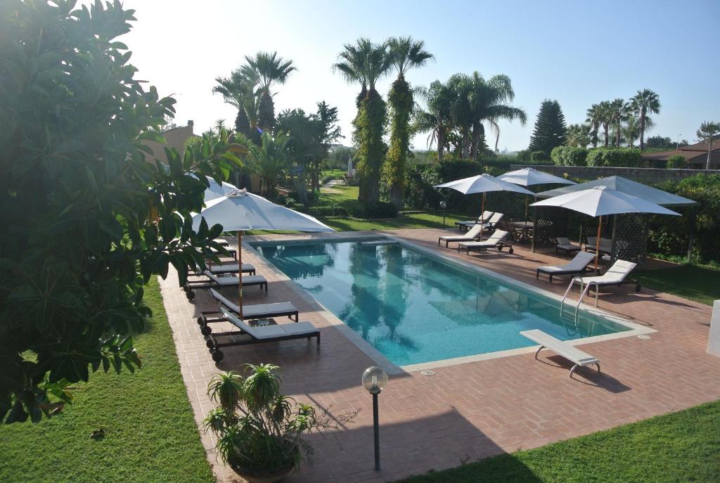 a swimming pool with lounge chairs and umbrellas at Villa Carlotta Resort in San Leone