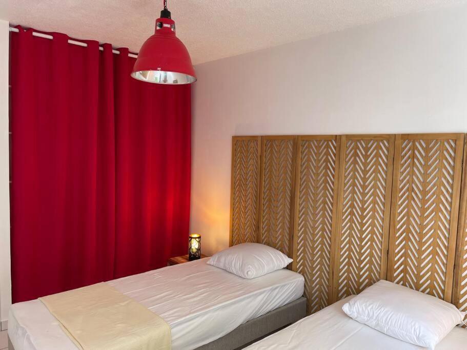 una camera con due letti e una tenda rossa di T3 de Standing aux trois ilets / Vue Mer a Les Trois-Îlets