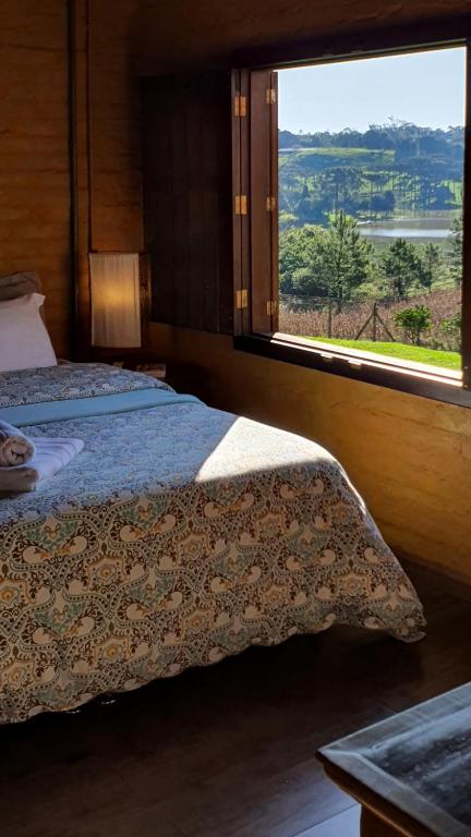 a bedroom with a bed and a window with a view at Loft romântico na Serra - natureza e fogão a lenha in Garibaldi